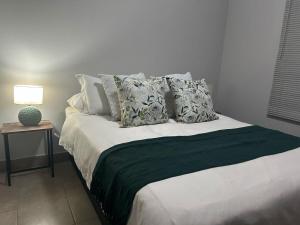 a bedroom with a bed with pillows and a lamp at Kufihliwe Lodge in Ingogo
