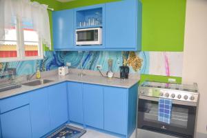 a blue kitchen with a microwave and a stove at ZenBreak Grateful n02 - 1bd A in Bridgetown