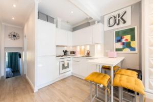 a kitchen with white cabinets and a table and two stools at Stylish flat in West Hampstead in London