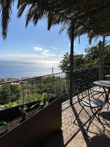 ein Balkon mit Tisch und Stühlen und dem Meer in der Unterkunft Casa de basalto in Caniço