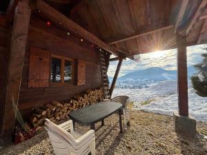 une véranda d'une cabane en rondins avec une table et des chaises dans l'établissement Chalet confortable à Méaudre pour 8 pers, vue imprenable - FR-1-737-98, à Méaudre