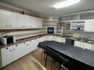 a kitchen with white cabinets and a black table at Casa Lidia, ideal familias y grupos in O Grove
