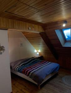 a bed in a room with a wooden ceiling at La Verrière du Sancy in Picherande