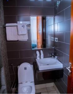 ダル・エス・サラームにあるMeridian CA Hotelのトイレ、洗面台、鏡のあるバスルーム