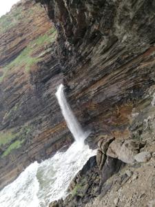 une cascade sur le côté d'une falaise dans l'établissement Mbotyi Mnceba Cottage, à Lusikisiki