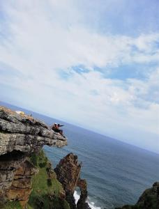 un groupe de personnes assises sur une falaise surplombant l'océan dans l'établissement Mbotyi Mnceba Cottage, à Lusikisiki