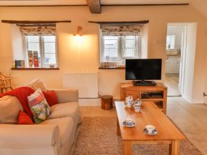 un salon avec un canapé et une télévision dans l'établissement Hope Cottage, à Beer