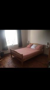 una camera da letto con un letto con lenzuola rosa e una finestra di Maison à la campagne Grande cuisine tous équipés, grand salon , 3 chambres avec lits doubles, salle de bain et toilettes a Fournols