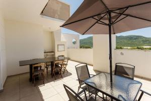 Un balcón con una mesa y sillas y una sombrilla. en Apartamentos com Piscina em Floripa - CAC, en Florianópolis