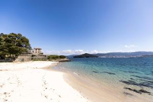 a beach with a house and the ocean w obiekcie Covelodge - Piso a pocos metros de la playa w mieście Pontevedra