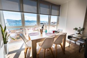una sala da pranzo con tavolo, sedie e una grande finestra di Covelodge - Piso a pocos metros de la playa a Pontevedra