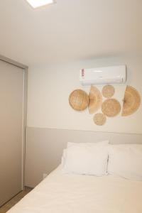 a bedroom with a white bed with baskets on the wall at DUNA HOUSE, apartamento beira mar em ARACAJU in Aracaju +14 photos