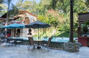 a table and chairs with umbrellas next to a pool at Hotel Paraíso Encantado in Xilitla