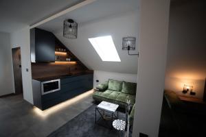a living room with a green couch and a kitchen at Apartman Elephant in Novi Sad