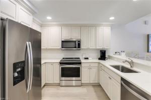 a kitchen with white cabinets and a stainless steel refrigerator at Bellasera Resort in Naples