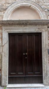 una gran puerta de madera en un edificio de piedra en Casa Piccolomini, en Ascoli Piceno