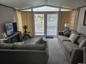 uma sala de estar com um sofá e uma TV em JJs Lodge Ebor em Allerthorpe
