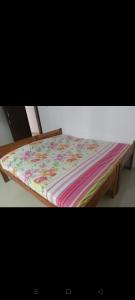 a wooden bed with a colorful blanket on it at Aswathy Bhavan in Palakkad
