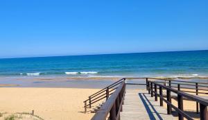 a wooden boardwalk leading to a beach with the ocean at Eldorado Apartment La Mata in La Mata