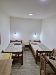 twee bedden in een kamer met een tafel en stoelen bij Konak Kod Gorana 1 in Subotica