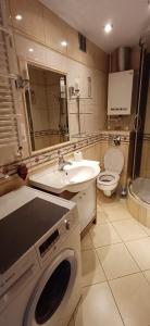 a bathroom with a washing machine and a sink at Słoneczny Apartament in Szczecinek +9 photos