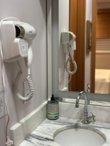 a bathroom sink with a hair dryer and a phone at Apto da Fé in Cachoeira Paulista +27 photos