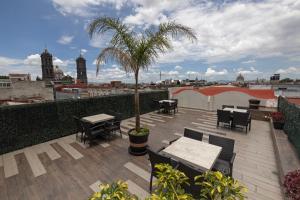 a patio with tables and chairs and a palm tree on a roof at Hotel Gala in Puebla