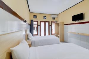 a bedroom with two beds and a tv on the wall at Townhouse Oak Legian Near Kuta Beach Formerly Sayang Maha Merta in Legian +32 photos
