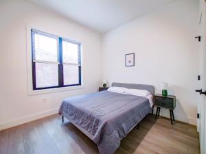 a white bedroom with a bed and a window at New Modern 2BR Apartment - minutes to NYC in Bayonne