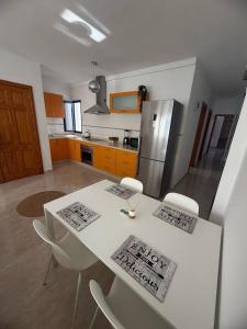 eine Küche mit einem weißen Tisch mit Stühlen und einem Kühlschrank in der Unterkunft Casa Velalatina in La Santa