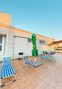 a patio with two lawn chairs and a green umbrella at Coastal Nest Apartments in Durrës