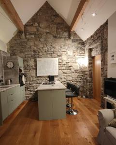 a kitchen with a stone wall and a desk with a computer at The Burren, Cozy Cottage, County Clare in Carran
