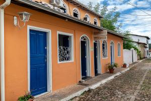 an orange building with blue doors on a street at Pousada Nativos Lençois in Lençóis