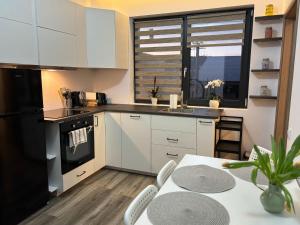 a kitchen with white cabinets and a table and a window at Anka apartman in Sovata
