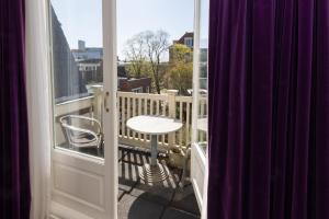 a balcony with a table and a stool on a balcony at Flora's Palace - The Hague Scheveningen in The Hague