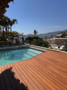a swimming pool on top of a house with a wooden deck at Casa con vista a la bahía in Acapulco