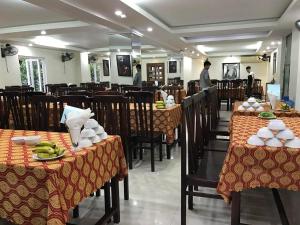 Thương Xà (2)にあるPhong Lan Hotel Cửa Lòの背景に人が立つテーブルと椅子が備わるレストラン +4枚の写真