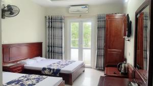 a hotel room with two beds and a window at Phong Lan Hotel Cửa Lò in Thương Xà (2)