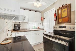 a kitchen with white cabinets and a stove top oven at Suncatcher Cottage 1508-2nd Avenue B in Tybee Island