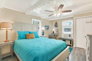 a bedroom with a blue bed and a ceiling fan at Suncatcher Cottage 1508-2nd Avenue B in Tybee Island