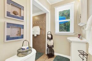 a bathroom with a sink and a toilet and a shower at Suncatcher Cottage 1508-2nd Avenue B in Tybee Island +32 photos