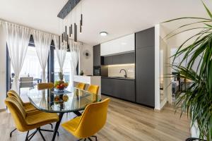a kitchen and dining room with a glass table and yellow chairs at MY DALMATIA - Sea view Villa Rica in Podvršje +72 photos