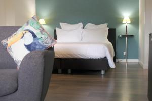a bedroom with a bed and a chair and a couch at Les Chambres Lauryvan in Saint-Junien