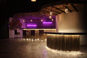 a bar in a room with chairs and purple lights at Río Celeste Poshtel Tayrona - Zaino in Calabazo