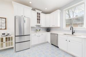 a kitchen with white cabinets and a stainless steel refrigerator at Stunning 2 Bedroom Apt in Historic Springfield in Jacksonville