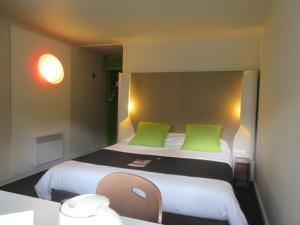 Habitación pequeña con cama con almohadas verdes en Campanile Bayeux, en Bayeux