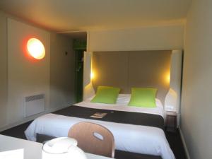 a small room with a bed with green pillows at Campanile Bayeux in Bayeux