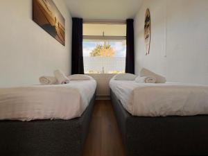 two beds in a room with a window at Reumann Holiday Apartments De Schelp 12 in Zandvoort