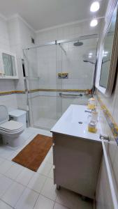 um banheiro com chuveiro, pia e vaso sanitário em Villas Terrace Apartment na Praia de Mira