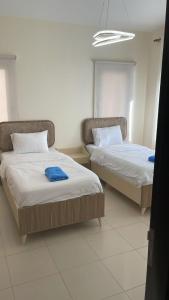 two beds sitting next to each other in a room at E25 TWO BEDROOM APARTMENT AT Samarah Resort in Sowayma +71 photos
